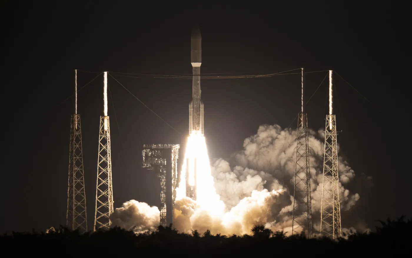 Atlas V rocket lifting off between lightning towers at night on the STP-3 mission